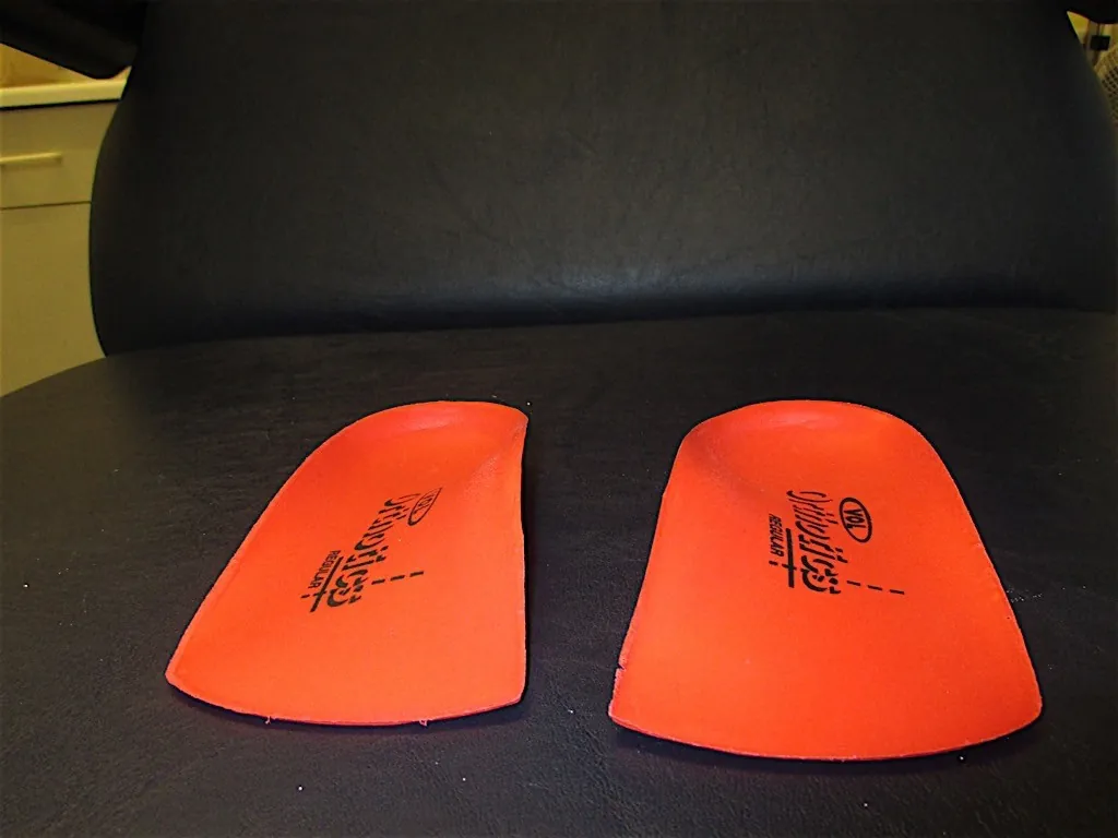 A pair of orange insoles on a black treatment chair