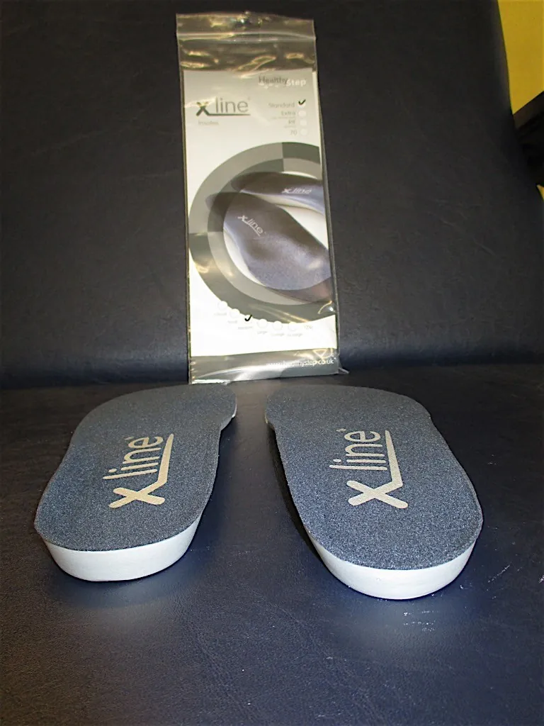 A pair of Xline insoles in front of their packaging
